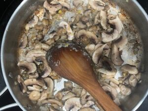 Mushrooms cooking with onion, garlic, and ginger in a pan for AIP Chicken Mongolian Style, a gut health recipe that is gluten free, dairy free, soy free, and nightshades free.