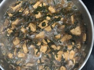 AIP Chicken Mongolian Style simmering in a pan with chicken, mushrooms, and dandelion greens. Gut health friendly, gluten free, dairy free, soy free, and nightshades free.