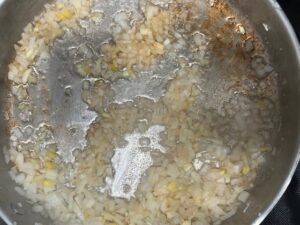 Onion, ginger, and lemongrass sautéing in a skillet for AIP Thai Coconut Chicken.