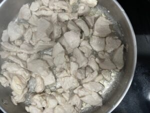 Chicken breast pieces browning in a skillet for AIP Thai Coconut Chicken recipe.