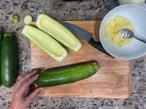 Preparing zucchini for AIP Zucchini Boats by slicing and scooping, gluten free, dairy free, nightshades free recipe for the autoimmune diet.