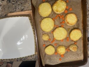Roasted white sweet potato rounds and carrot slices on a parchment-lined baking sheet for Deviled No Eggs Potatoes.