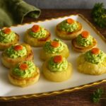 Deviled No Eggs Potatoes on a white platter with avocado guacamole and carrot slices, parsley and lemon garnish. Nightshade free, gluten free, egg free, dairy free.