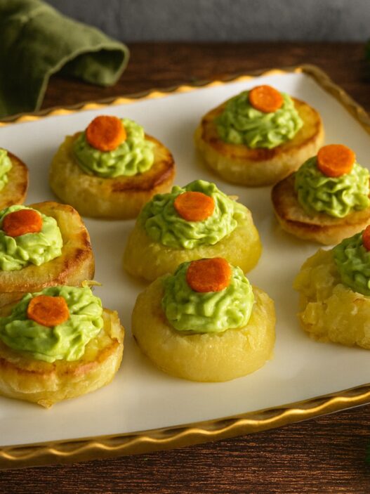 Deviled No Eggs Potatoes on a white platter with avocado guacamole and carrot slices, parsley and lemon garnish. Nightshade free, gluten free, egg free, dairy free.