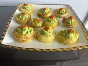 Plated Deviled No Eggs Potatoes topped with avocado filling and roasted carrot slices on a white square platter.