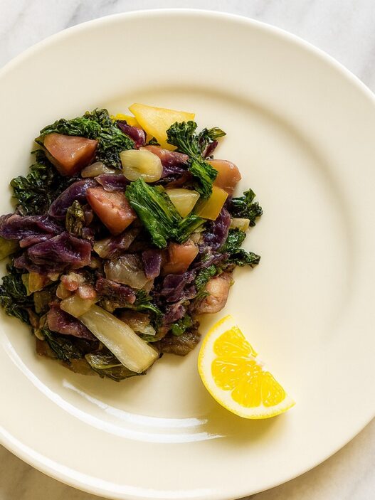 Rainbow Veggie Stew served on a cream plate with kale, cabbage, parsnips, and a lemon wedge. AIP, anti-inflammatory, and gut-healing vegetable dish.