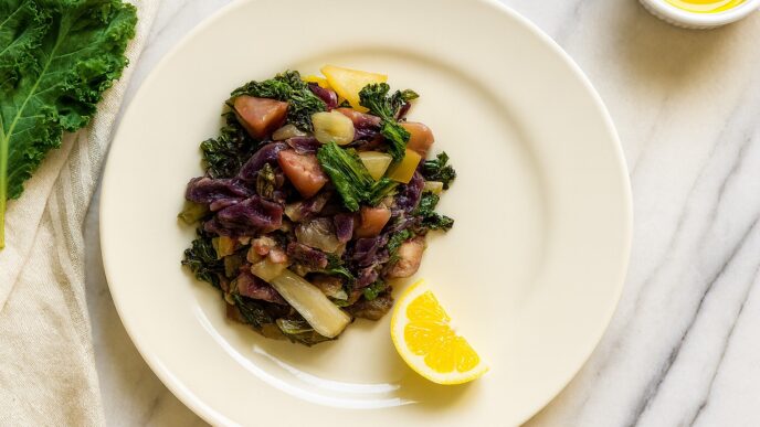 Rainbow Veggie Stew served on a cream plate with kale, cabbage, parsnips, and a lemon wedge. AIP, anti-inflammatory, and gut-healing vegetable dish.