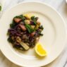 Rainbow Veggie Stew served on a cream plate with kale, cabbage, parsnips, and a lemon wedge. AIP, anti-inflammatory, and gut-healing vegetable dish.