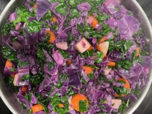 Sweet Potato Cabbage Stew simmering with red cabbage, carrots, sweet potato, and kale in a pot.