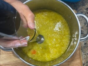 Blending cooked cauliflower, carrots, and celery with an immersion blender to make AIP Cauliflower Cream Soup, a dairy free and anti-inflammatory recipe.