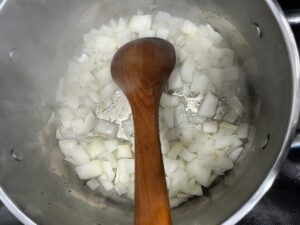 Cooking onions in a stainless steel pot with avocado oil as the first step for AIP Cauliflower Cream Soup, a dairy free anti-inflammatory recipe.