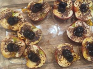 Baked Apples with Cherries ready for the oven, topped with cinnamon, maple syrup, and sweet cherries.