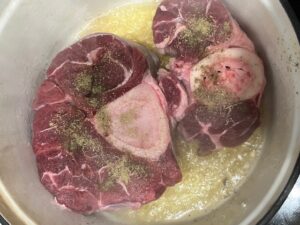 Best AIP Osso Buco beef shanks searing on top of sautéed vegetables in a pot.