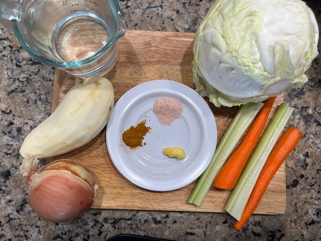 Cabbage and Potato Soup ingredients dairy free gluten free AIP-friendly including cabbage, potato, carrot, celery, onion, ginger, turmeric, sea salt, and water on a wooden board